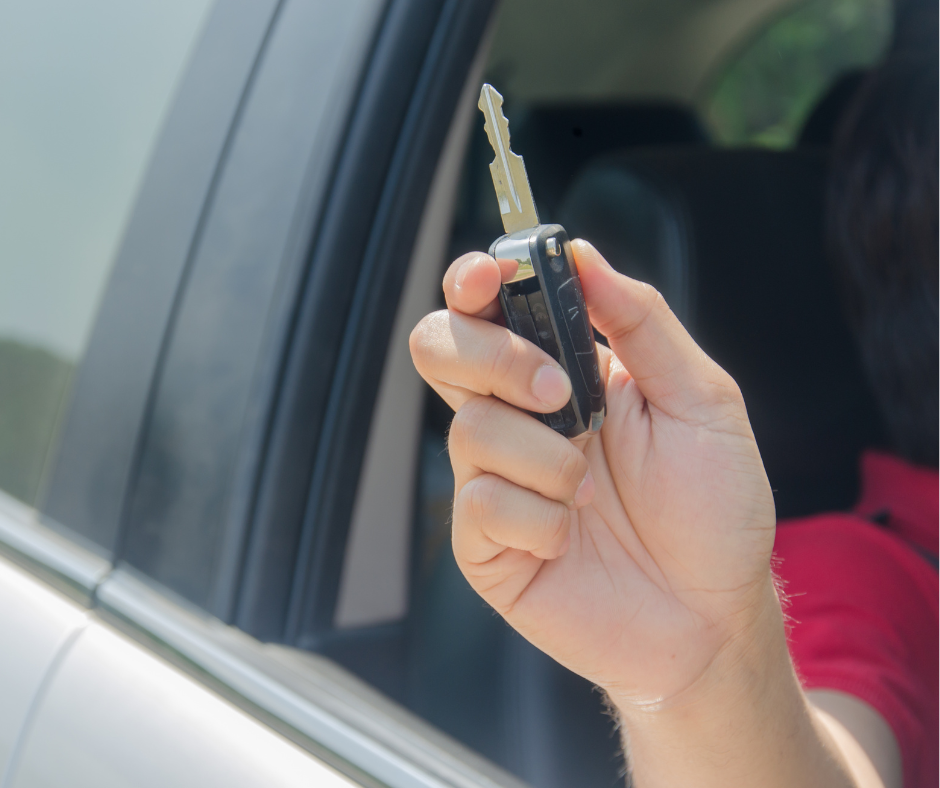 Hand houdt autosleutel uit autoraam