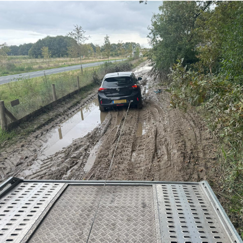 Takelwagen trekt auto uit modder